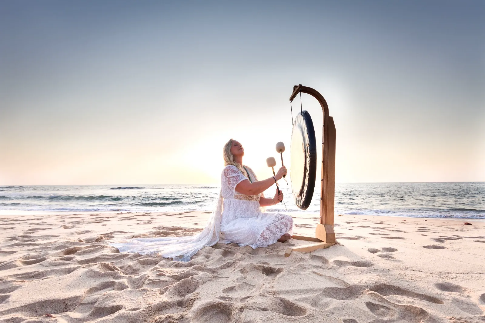 Sharmila Devasya performing gong sound healing on the beach in Aljezur, Portugal
